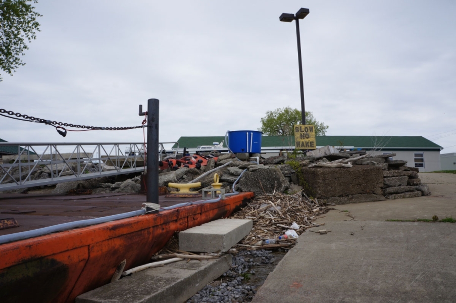 View of a dock and boat ramp. Near the top of the slope is a large barrel with a hose that goes down over the dock.