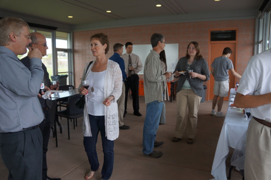 People mingling in a pavilion with glass walls.