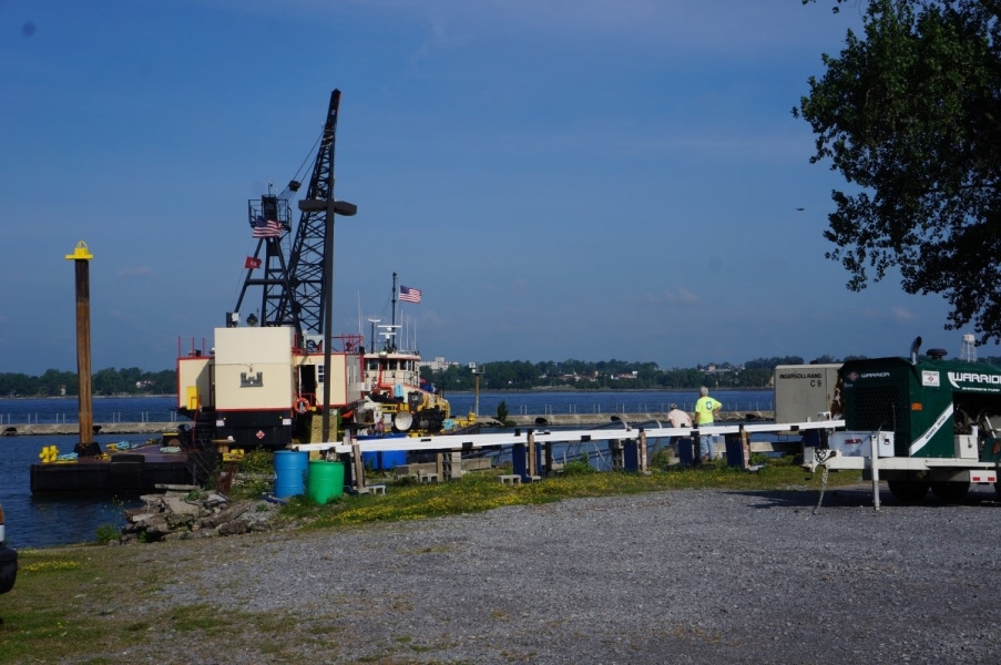 A tug and a barge with a crane approach a dock