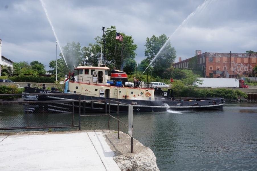 A tug boat shoots water cannons into the sky