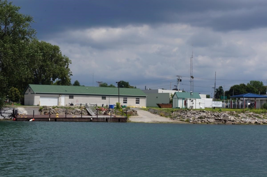 A one-story building with a boat ramp and dock along the water.