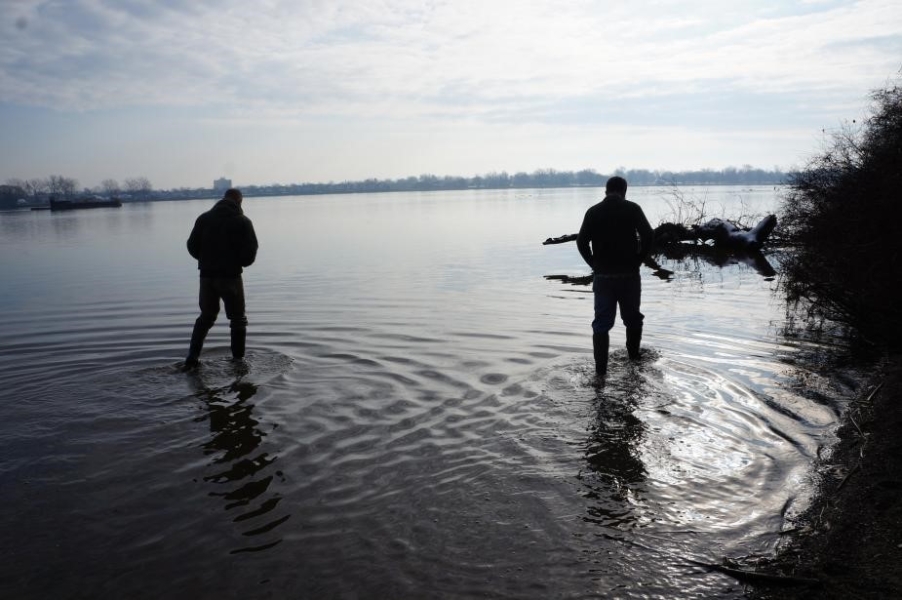 Two people wade through shallow water.