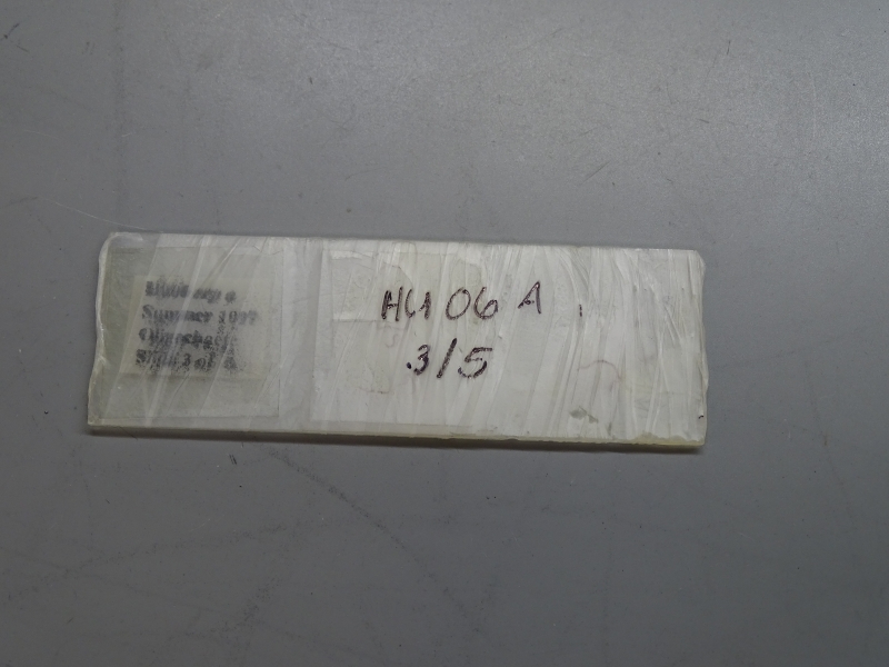 A microscope slide wrapped in film. The label is obscured, but there is writing on the film. "HU 06 A 3/5"