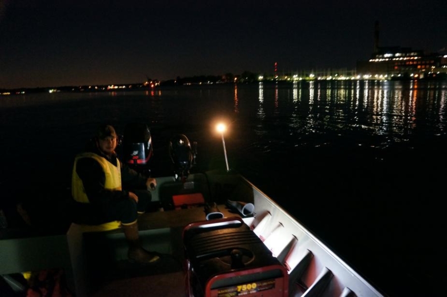 Nighttime picture of a person sitting in the back of a boat running the engine.