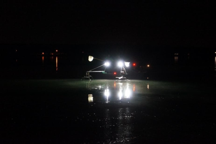 Nighttime picture of a boat with spotlights on the water