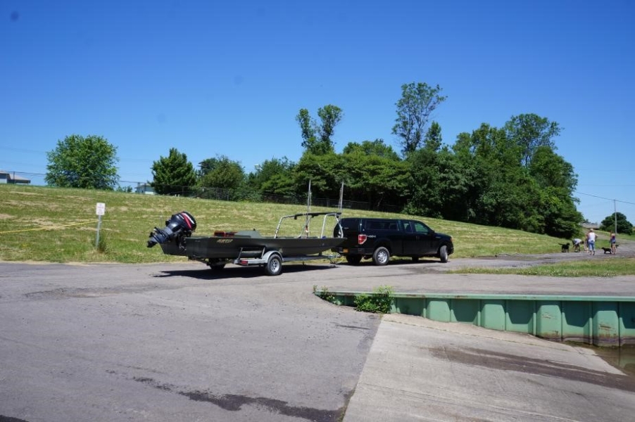 A truck and a boat on a trailer by a boat ramp.