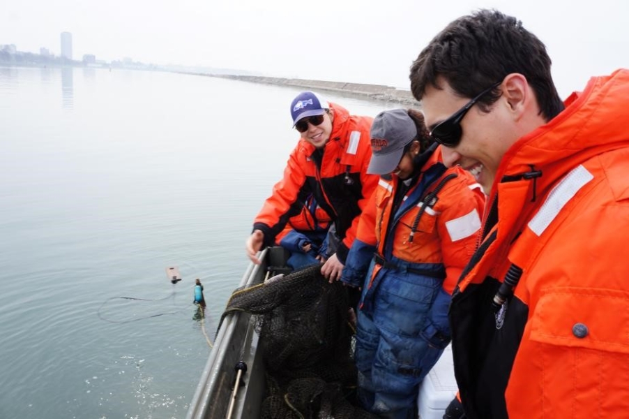 Students pulling the last of a black net onto a boat