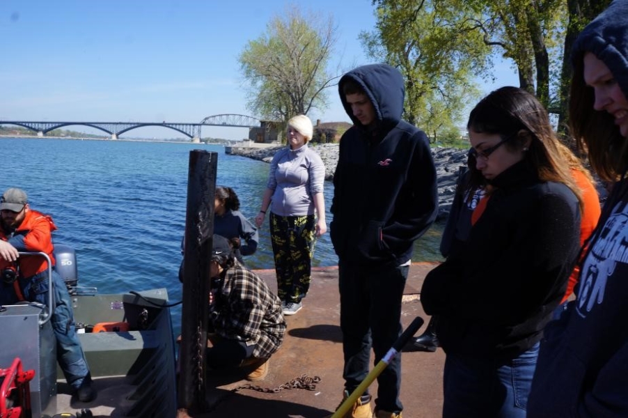 People stand on a dock next to a moored boat.