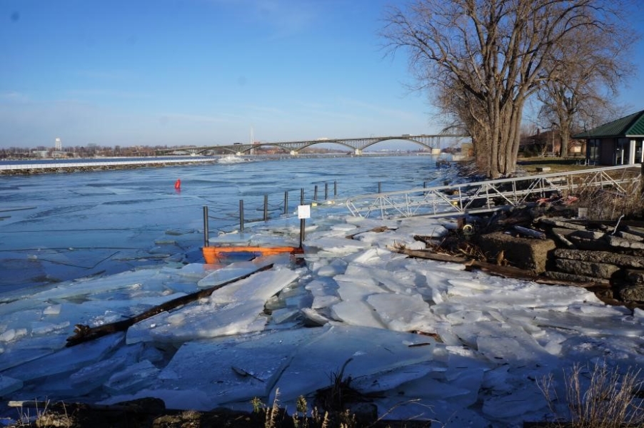 A boat dock and shoreline covered with broken sheets of ice.