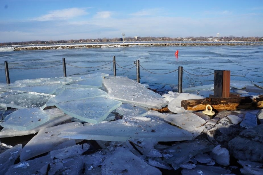 A boat dock covered with broken sheets of ice. The sheets of ice are at least 4 inches thick.