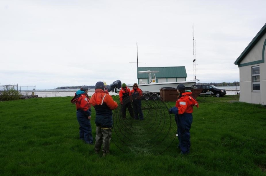 Students in flotation suits hold a conical trap net open on land. The picture is taken from front-on, looking toward the opening of the net.