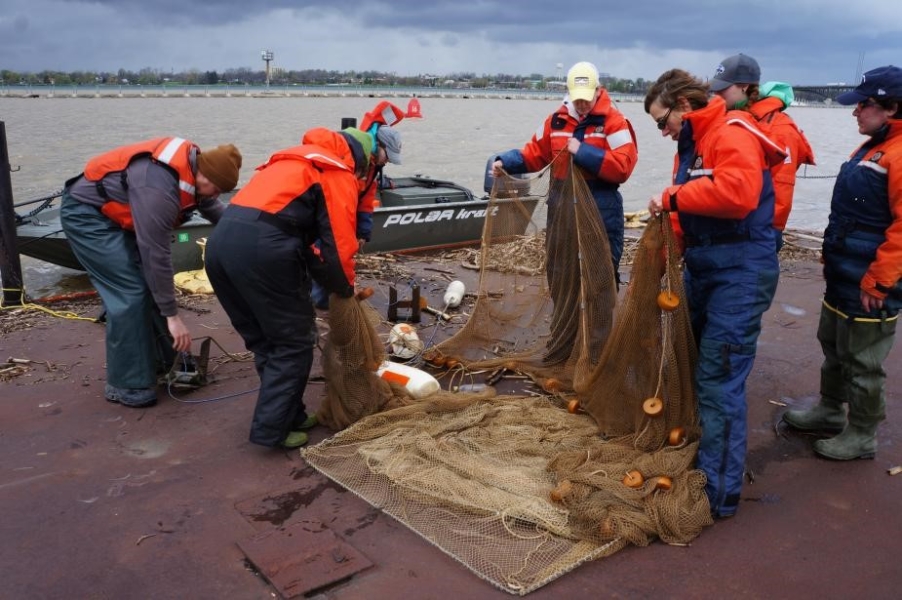 People in flotation suits laying out a large net on the dock.