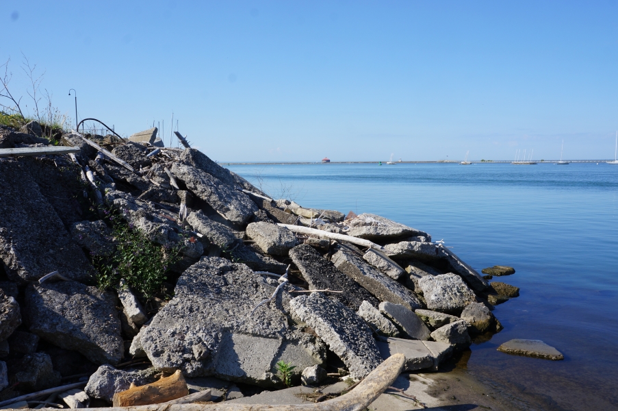 A pile of broken concrete pieces on the slope between the ground and the water.