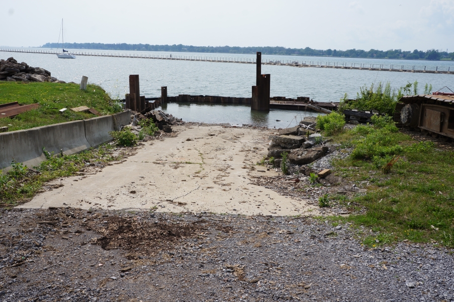 A boat ramp with a wall of steel beams surrounding the end of it. There is water on both sides of the wall.