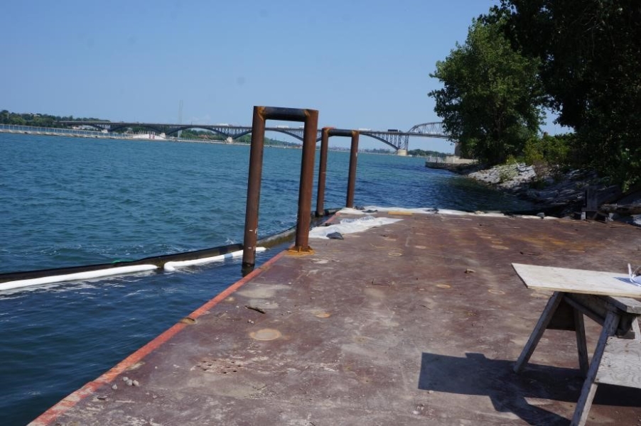 A metal surface by the water. Two U-shaped bars are attached to the side going into the water.