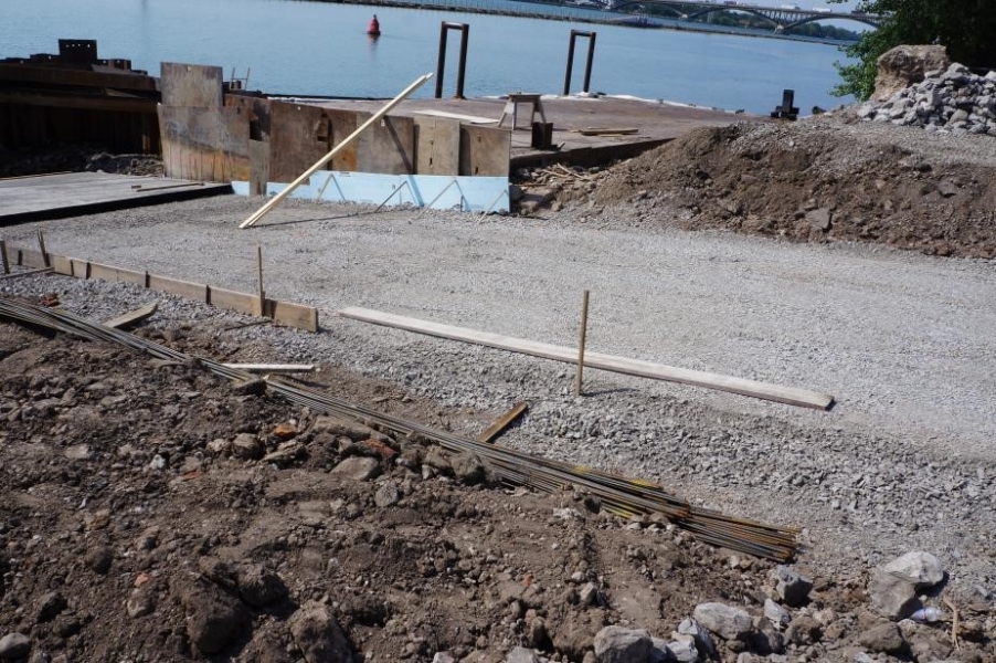 A driveway area in a construction site that is covered with gravel. Stakes are used along the edges of the driveway.