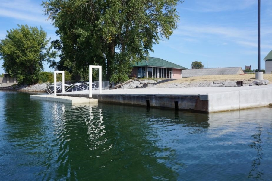 A concrete dock with two white metal u-shaped bars that connect to a floating platform.