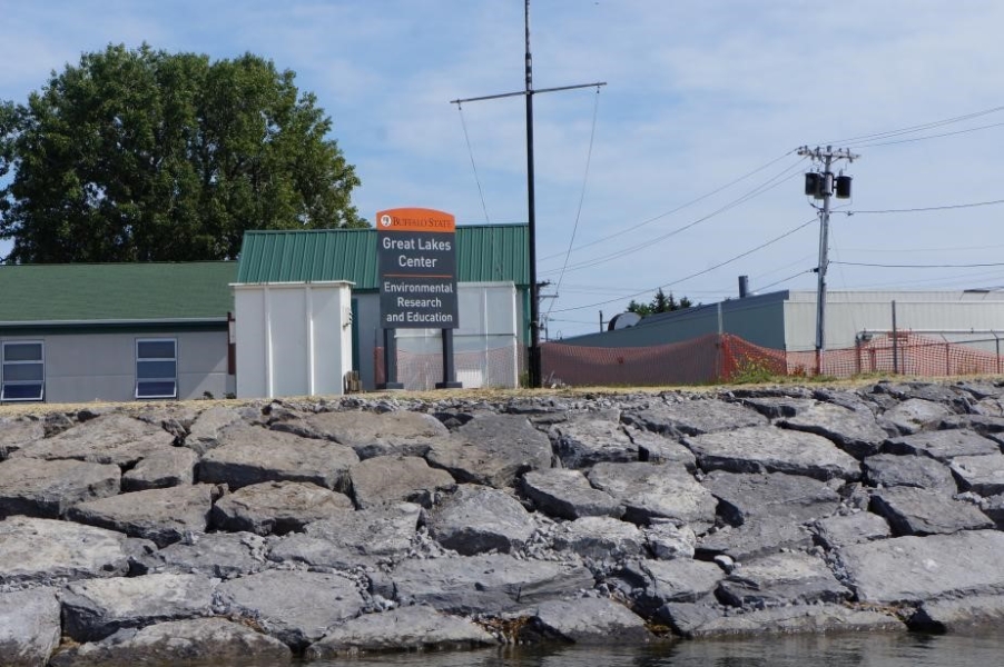 A sign in front of a building up a slope of neatly placed boulders. The sign reads, "Great Lakes Center - Environmental Research and Education."