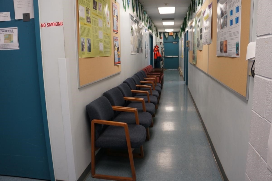 A line of chairs against the wall in a hallway.