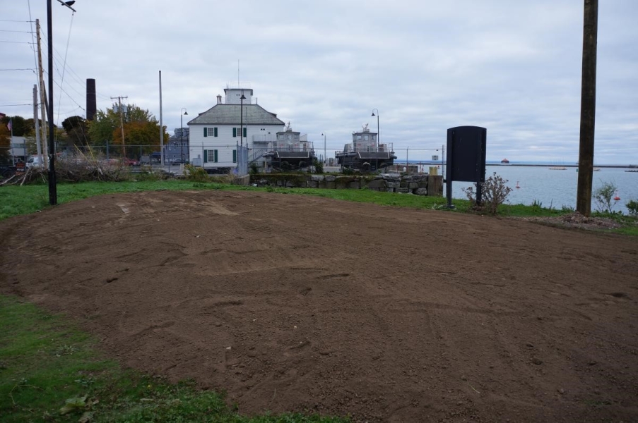 A large patch of dirt on the ground by the waterfront.