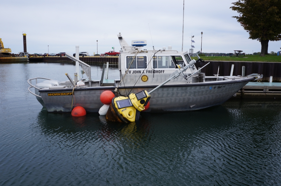 A boat at dock with a buoy tied to its side. There are other floats on the buoy to keep it in position.