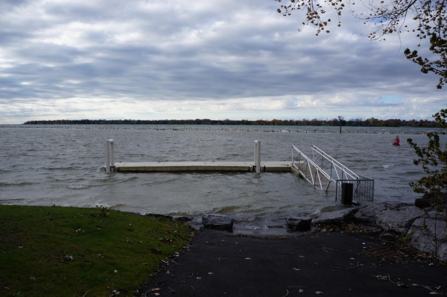 High water submerges a concrete dock but allows a metal ramp and floating dock to stay above water. The water level looks higher than normal since there is some water between the ramp and land.