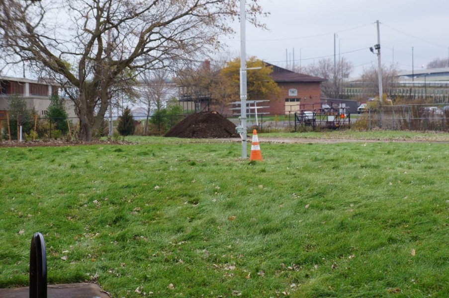 A metal pole with a crank in the middle of a field.