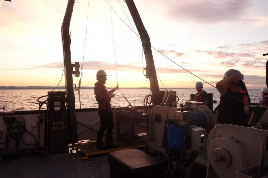 Four people working on the deck of a boat at sunrise or sunset