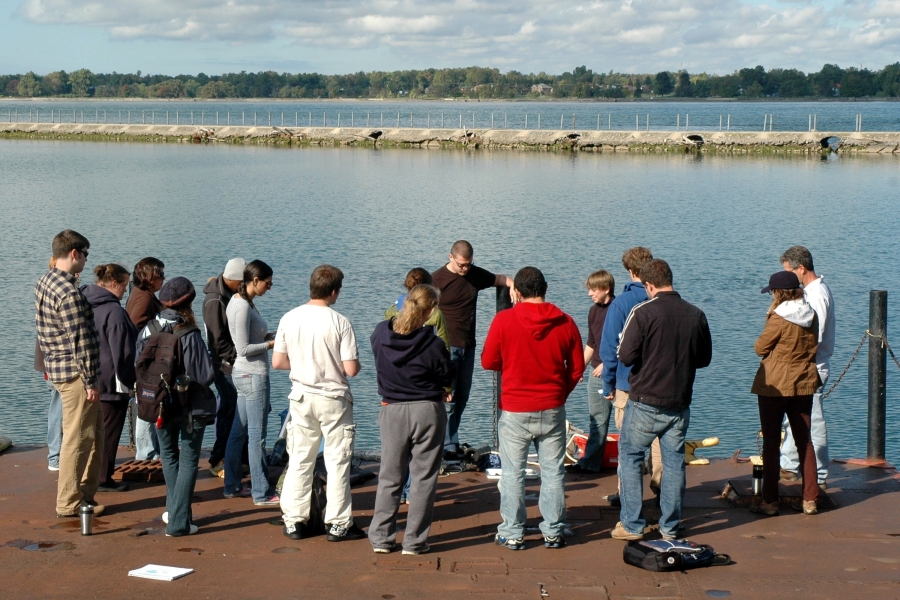 A group of people stand on a dock facing the water