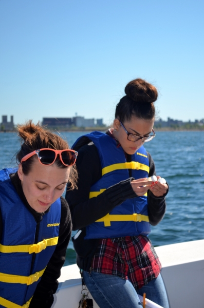 Students on a boat looking at small glass vials