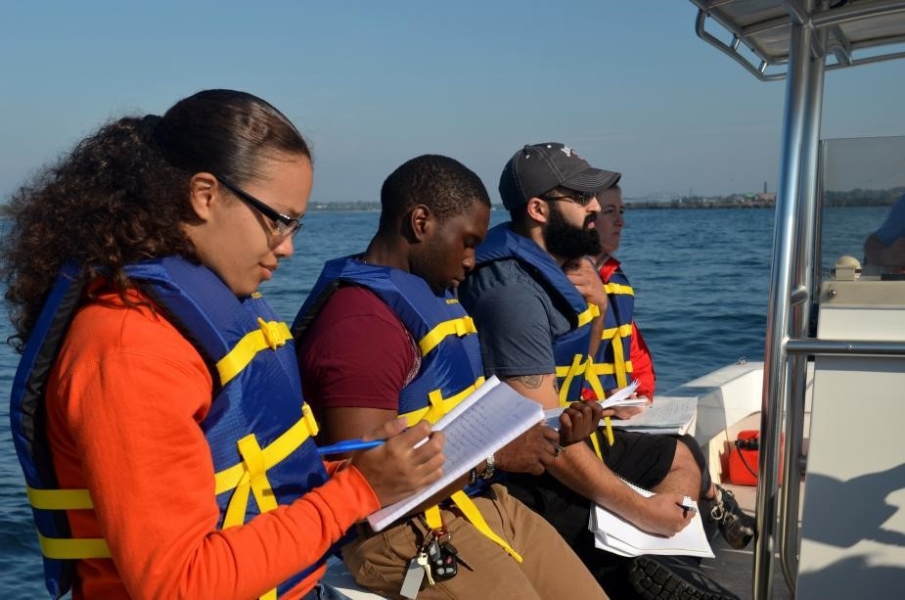 Students on a boat taking notes in a notebook