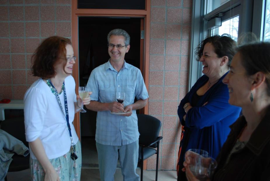 Four people stand talking and laughing