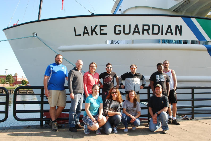 A group of people posing for a picture in front of a ship called Lake Guardian.