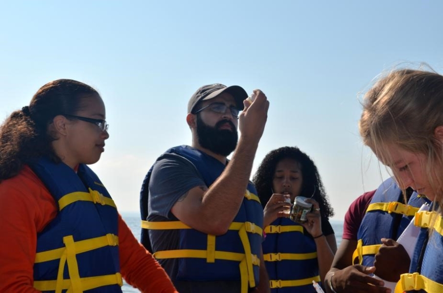 Students in life jackets looking at small glass vials