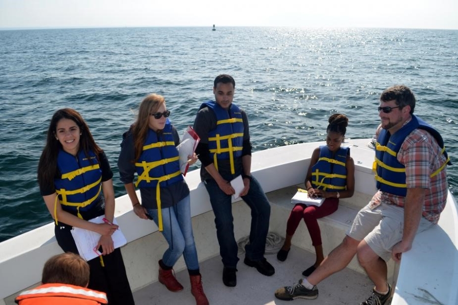 A group of students in life jackets in the bow of a fiberglass boat