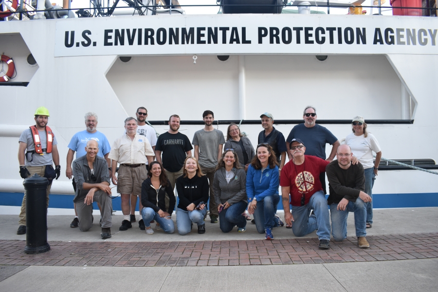 A group of people posing for a picture in front of a large boat labeled "U.S. Environmental Protection Agency."