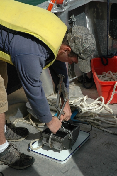 a person on a boat opens up a metal dredge sampler on a pan