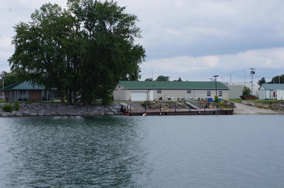 View from the water of a one-story building with a dock and ramp.