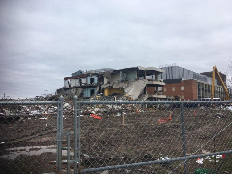 A construction site with a partly demolished building behind a chain-link fence.