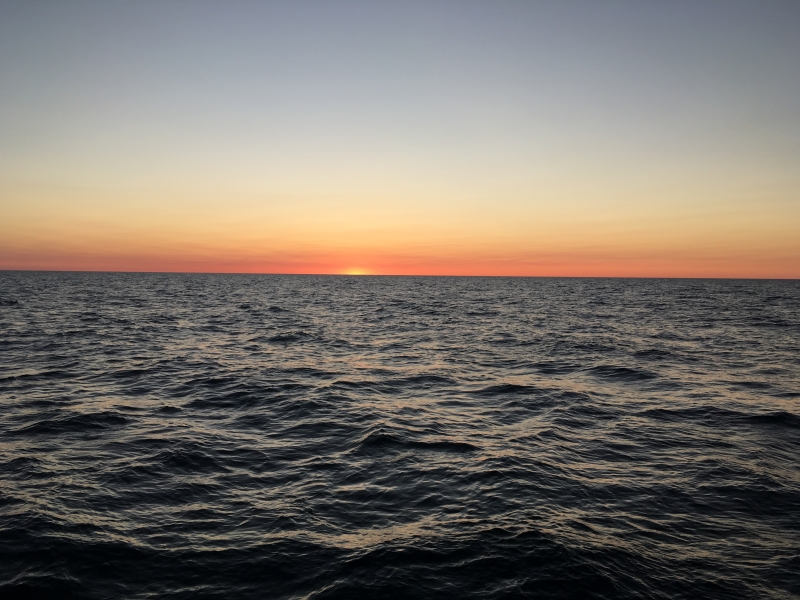 Sunrise over water, with the sun just barely peeking above the horizon