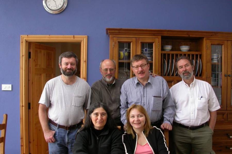 six people pose for a picture in a front a cabinet with dishes