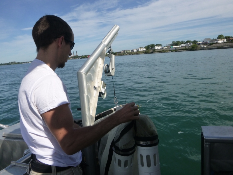 A person holds a net with two plastic buckets at the bottom, getting ready to put the net into the water.