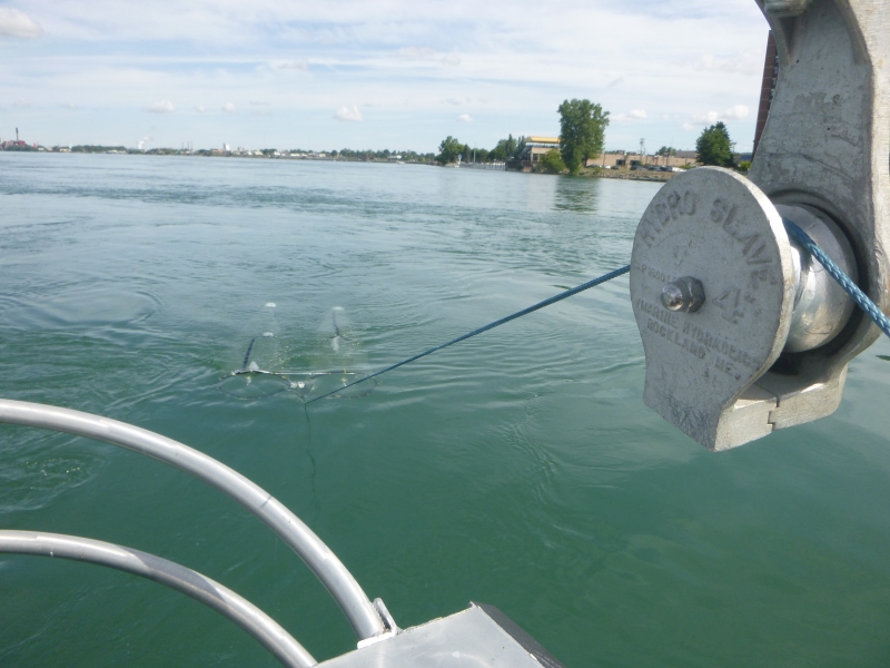 Rope going from a block and tackle on a boat, back to a net being towed through the water, just visible below the surface