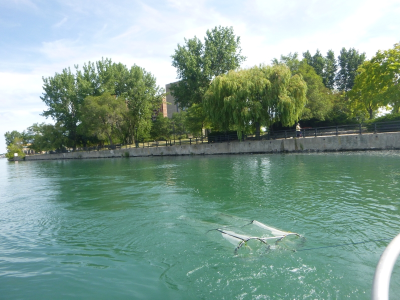 Two long round nets being towed through the water near the surface.