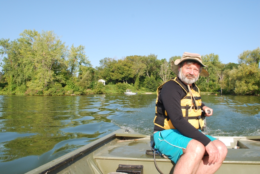 A person sitting at the back of a boat to operate the motor.