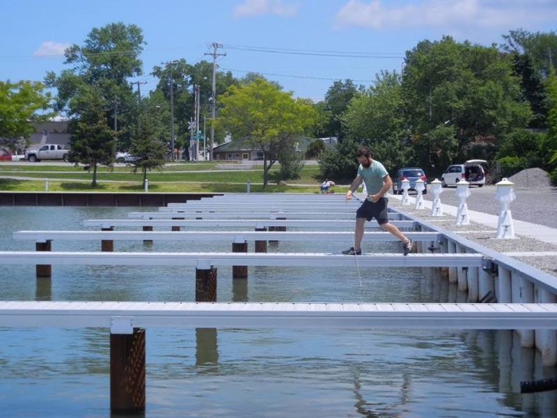 A person tows a net between the docks at an empty marina.