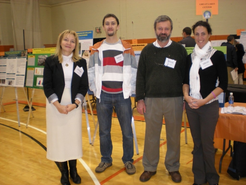 four people pose for a picture in a room full of posters on easels