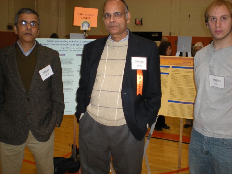 Three people pose for a picture in front of posters on easels at a conference