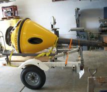The yellow body of a buoy sits on a trailer in a garage