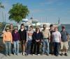 Ten people stand on a boat dock in front of a boat